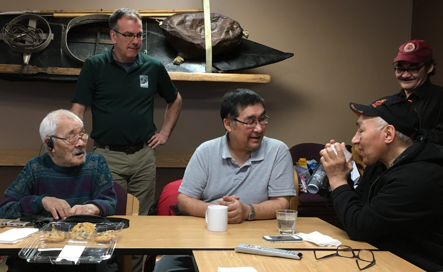 Seated from left are Sikumiut members Gamalie Kilukishak (deceased), Caleb Sangoya and David Angnatsiak (deceased) telling stories about sea ice in Mittimatalik in 2017. Standing from left are Dr. Trevor Bell and Malachi Arreak. Photo from: Memorial University